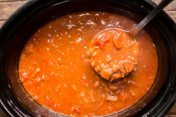 ladling beef enchilada chili from the slow cooker.