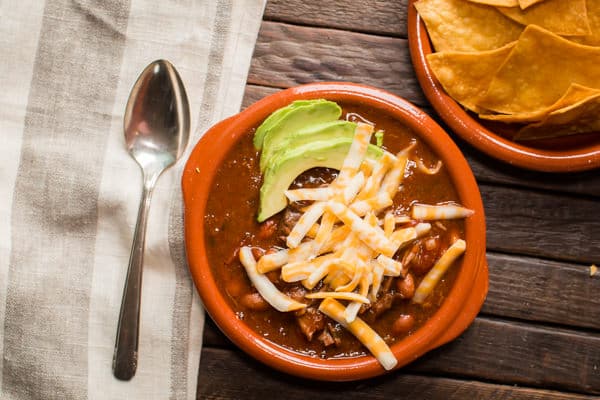 bowl of beef enchilada chili with chips on the side.