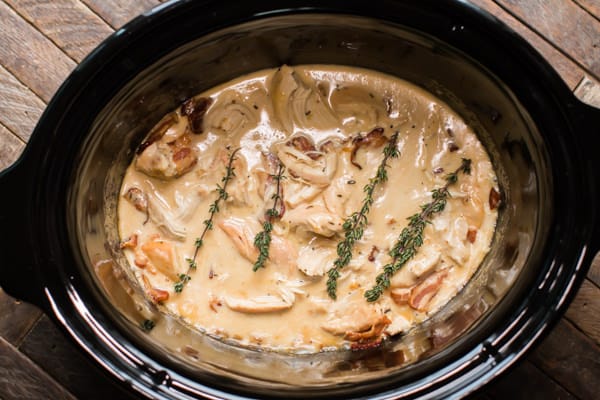 chicken breasts in gravy in a slow cooker garnished with dried thyme