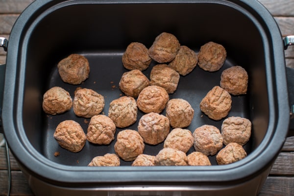 frozen meatballs on the bottom of a slow cooker.