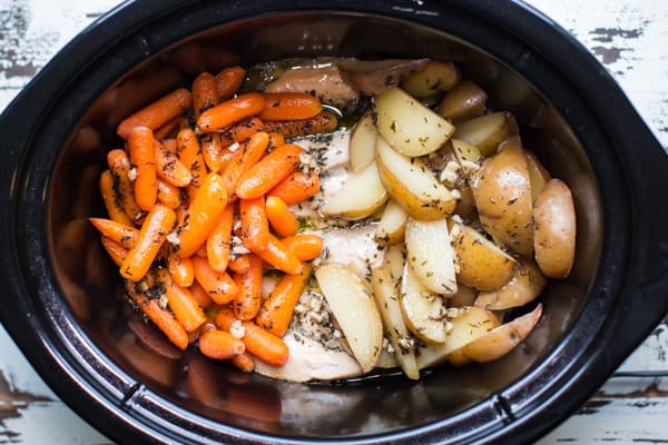 chicken, carrots and potatoes in a slow cooker.