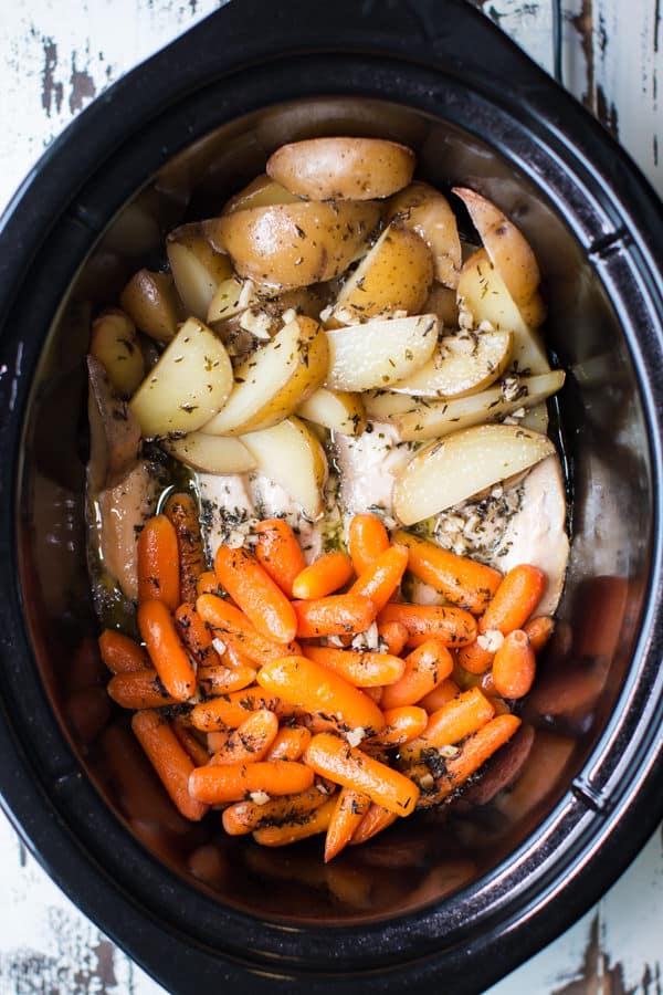 carrots, potatoes, and chicken tenders with buttery garlic sauce in a slow cooker.
