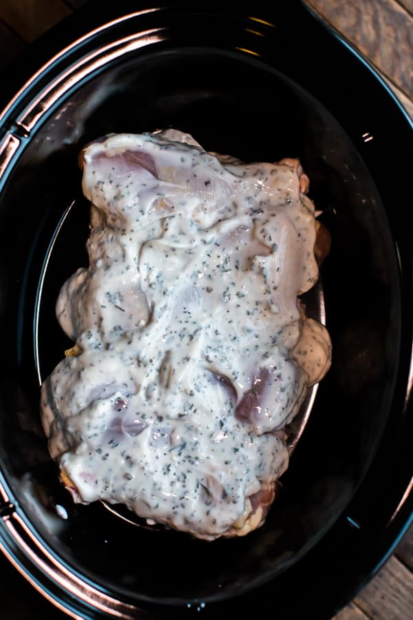 drumsticks in a slow cooker with yogurt mixture on top.