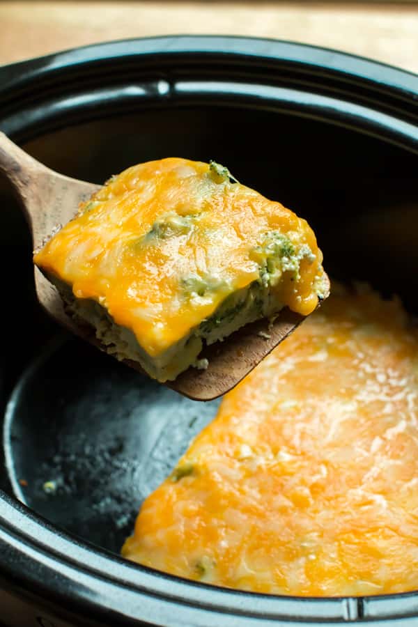 broccoli cheese quiche being lifted out of a slow cooker.