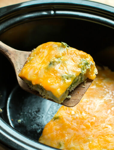 square or broccoli quice on a spatula. Slow Cooker in the background.