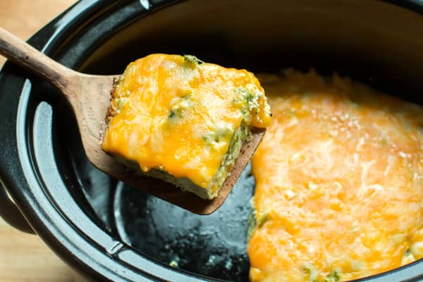 slice of broccoli cheese quiche on wooden spatula.