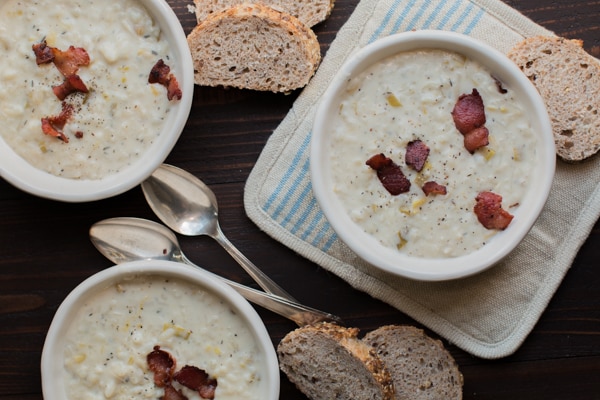 3 bowls of hashbrown soup and bread on a table.