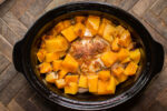 whole chicken in a slow cooker with butternut squash cubes, done cooking.