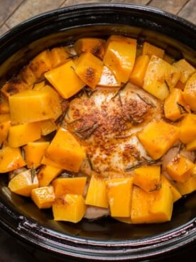 whole chicken in a slow cooker with butternut squash cubes, done cooking.