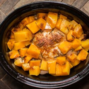 whole chicken in a slow cooker with butternut squash cubes, done cooking.