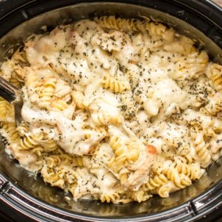 pesto mozzarella chicken pasta with metal spoon in it.