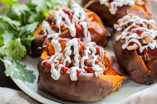 sweet potatoes stuffed with pulled pork garnished with cilantro