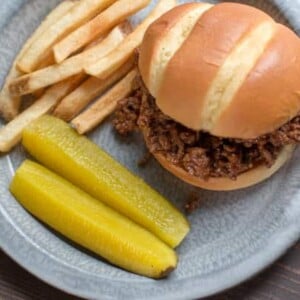 ground beef sandwiches with fries and pickles.