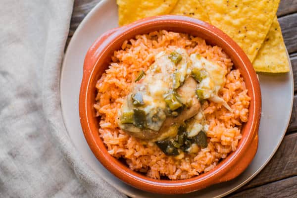 green chile chicken thigh on mexican rice in a bowl.