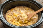 warm pineapple spoon cake in the slow cooker with wooden spoon in it.