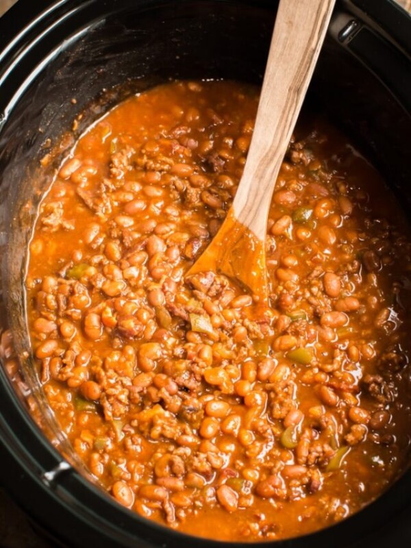 baked beans in slow cooker with wooden spoon.