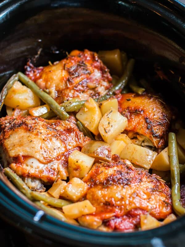 close up of chicken thighs and potatoes in a slow cooker.