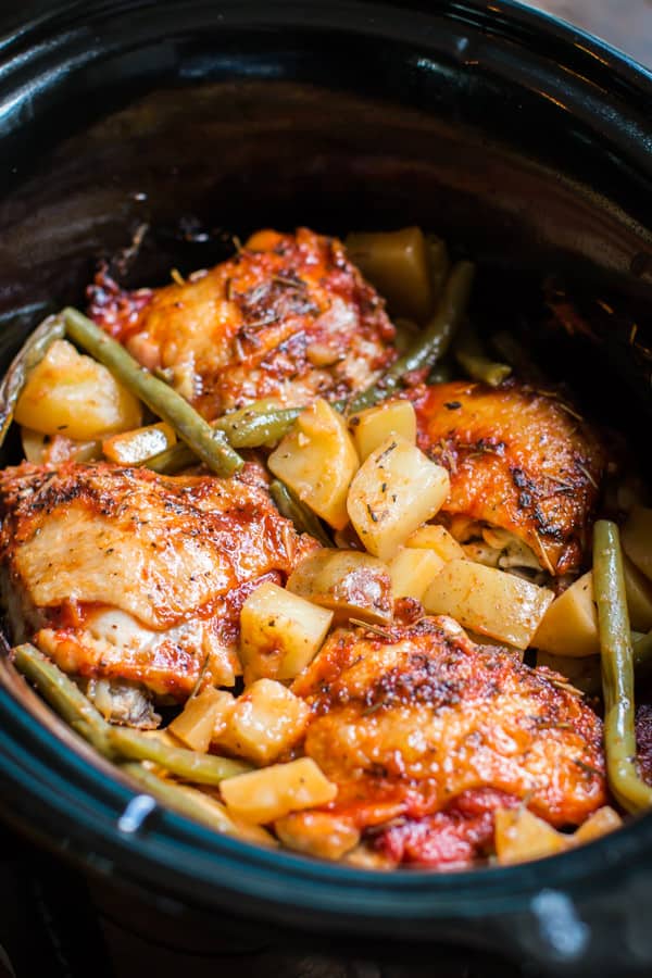 close up of chicken thighs and potatoes in a slow cooker.