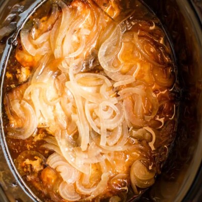 4 pork chops with onions and sauce in a slow cooker.