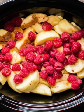 sliced apples, cinnamon and raspberries in a slow cooker.