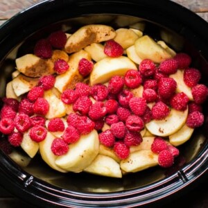 sliced apples, cinnamon and raspberries in a slow cooker.