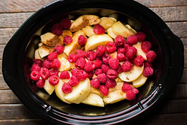 sliced apples, cinnamon and raspberries in a slow cooker.