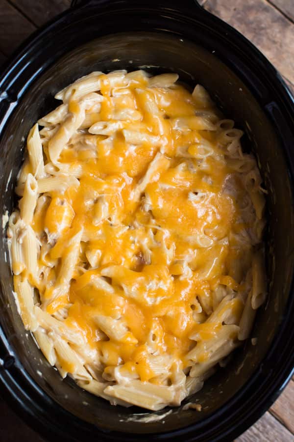 penne pasta cooked with cheese on top in a slow cooker.