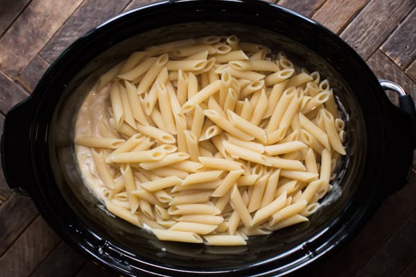 penne pasta cooked and creamy sauce in a slow cooker.