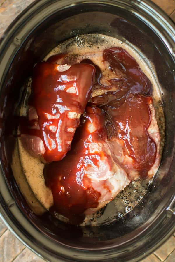 raw ribs with barbecue sauce and dr. pepper in a slow cooker.