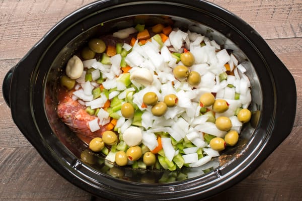 raw beef, onions, bell pepper, green olives and garlic in a slow cooker.