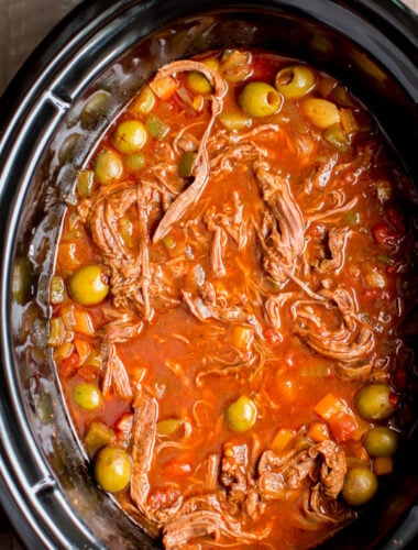 ropa vieja in vibrant sauce with plenty of olives in a slow cooker.