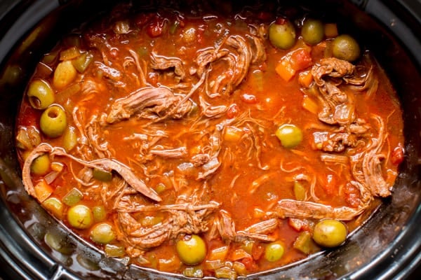 close up of ropa vieja with olives and sauce in the slow cooker.