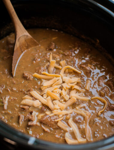 close up of texan chili in the slow cooker with wooden spoon in it.