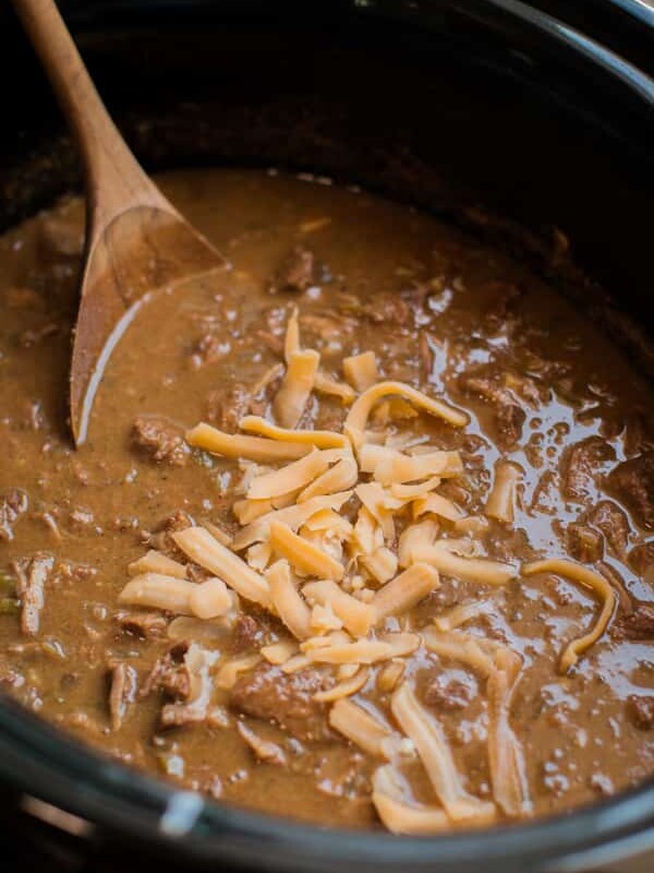 close up of texan chili in the slow cooker with wooden spoon in it.