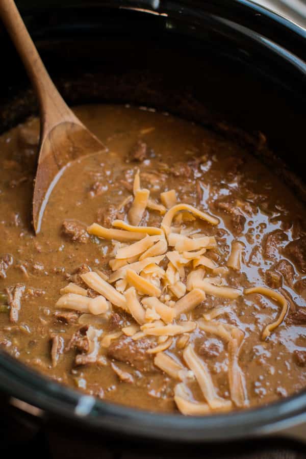 close up of texan chili in the slow cooker with wooden spoon in it.