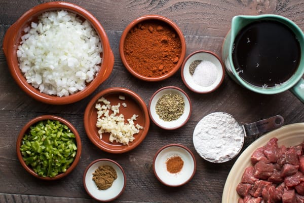 seasonings, broth, flour, jalapeno, onion on a wooden table.