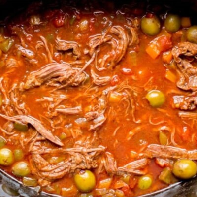 close up of ropa vieja in a slow cooker with plenty of green olives