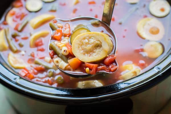ladle of summer minestrone soup in a slow cooker