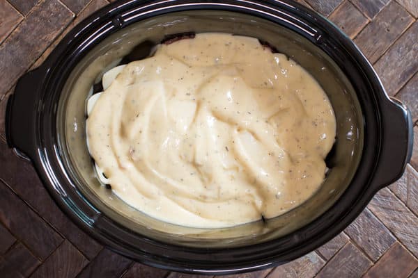cream of chicken soup mixture spread over chicken, ham and chicken in a slow cooker.