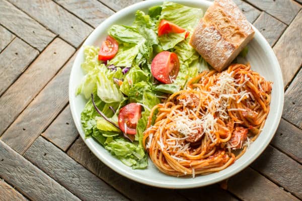plate of spaghetti, salad and bread.
