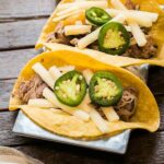 pork tacos with white cheese and jalapenos on top.