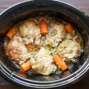 chicken thighs in sauce in a slow cooker with leeks and carrots.