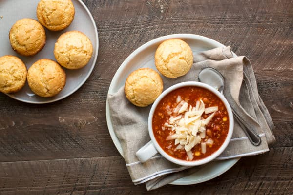 bowl of chipotle chili with corn bread muffins on the side.