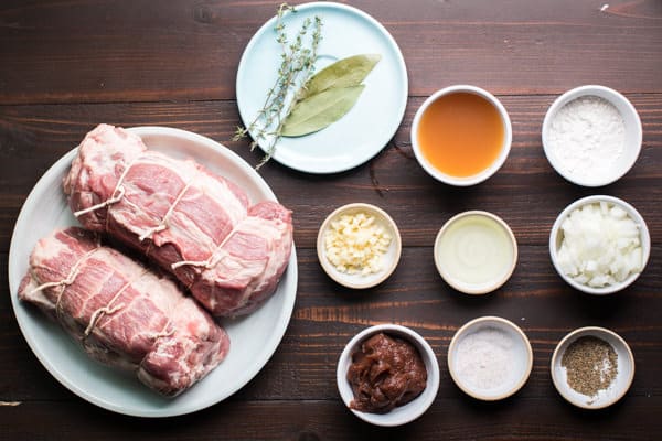 2 pork roasts, seasonings, cider, apple butter on a wooden table.