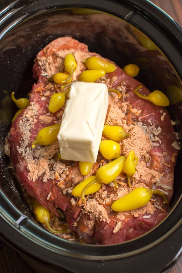 close up of raw chuck roast, peppers and butter