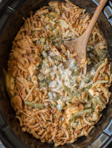 spoon in cheesy green bean casserole in slow cooker.