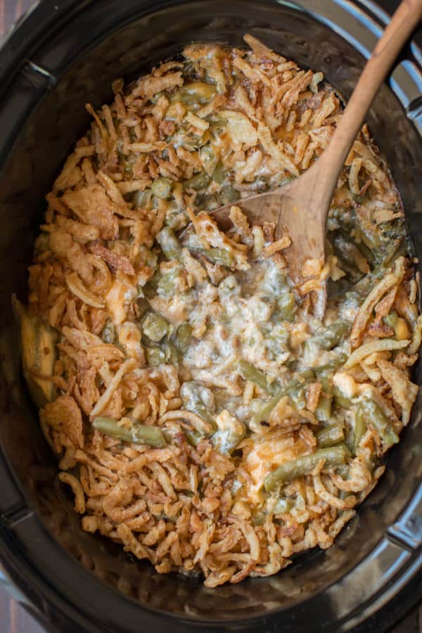 spoon in cheesy green bean casserole in slow cooker.