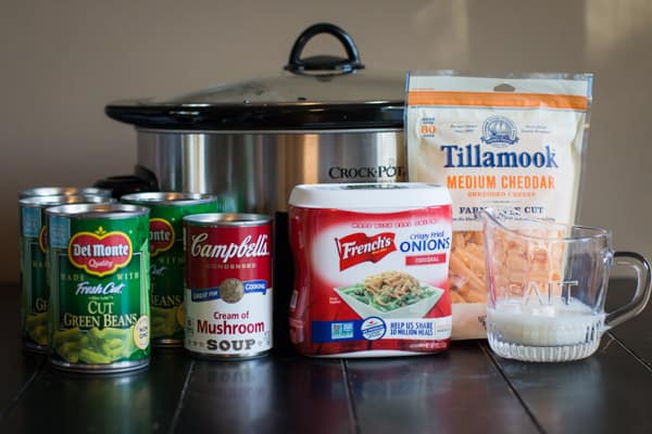 green beans, mushroom soup, French fried onions, cheese and milk in front of a slow cooker.