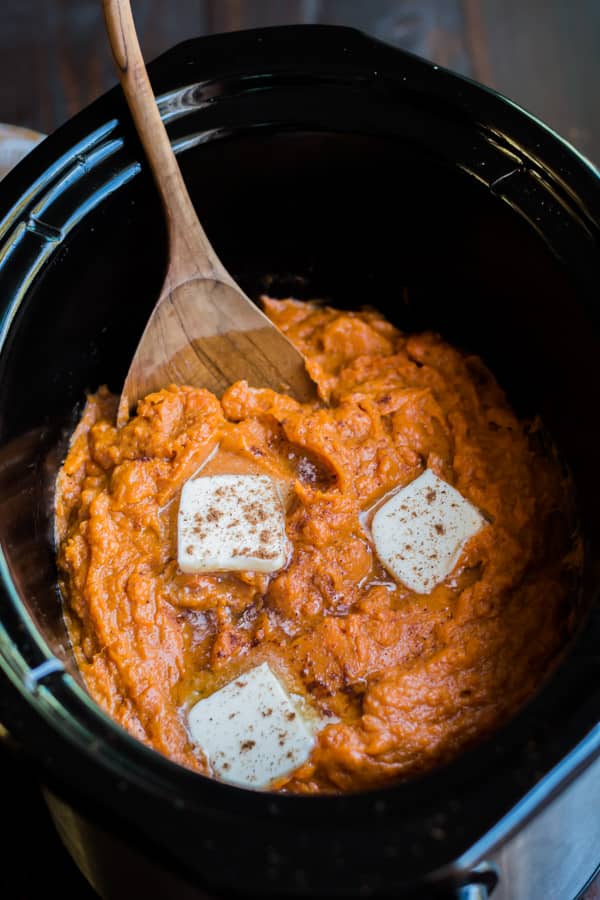 wooden spoon in mashed sweet potatoes in a slow cooker