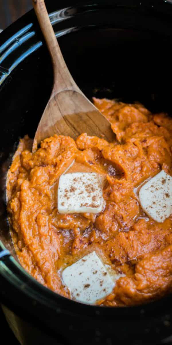 close up of mashed sweet potatoes with pats of butter on top.